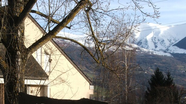 A sign reading "LE CABALIOS" in front of a building with a snow-covered mountain in the background.