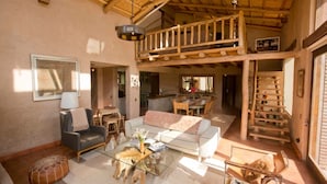A spacious living area with a high ceiling, a balcony, and a dining area. - Luxury house in Sacred Valley. Modern comfort, rustic style, stunning views (Urquillos Urubamba)
