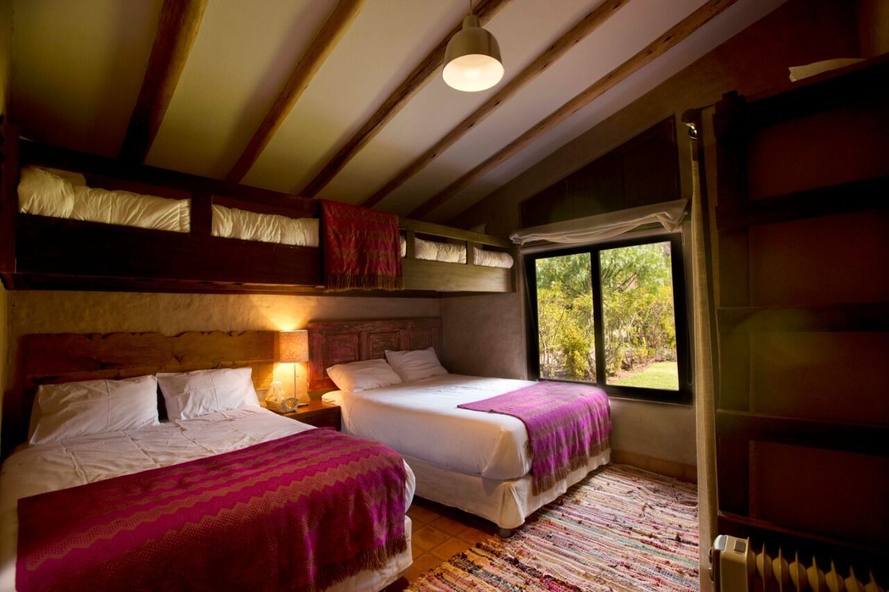 A cozy room with two beds, a window with a view, and a wooden ceiling.