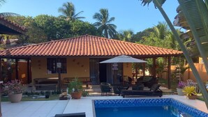 Un espace piscine doté d’une terrasse carrelée, d’un banc et d’une petite piscine.