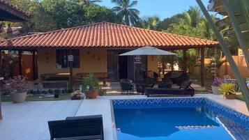 Un espace piscine doté d’une terrasse carrelée, d’un banc et d’une petite piscine.