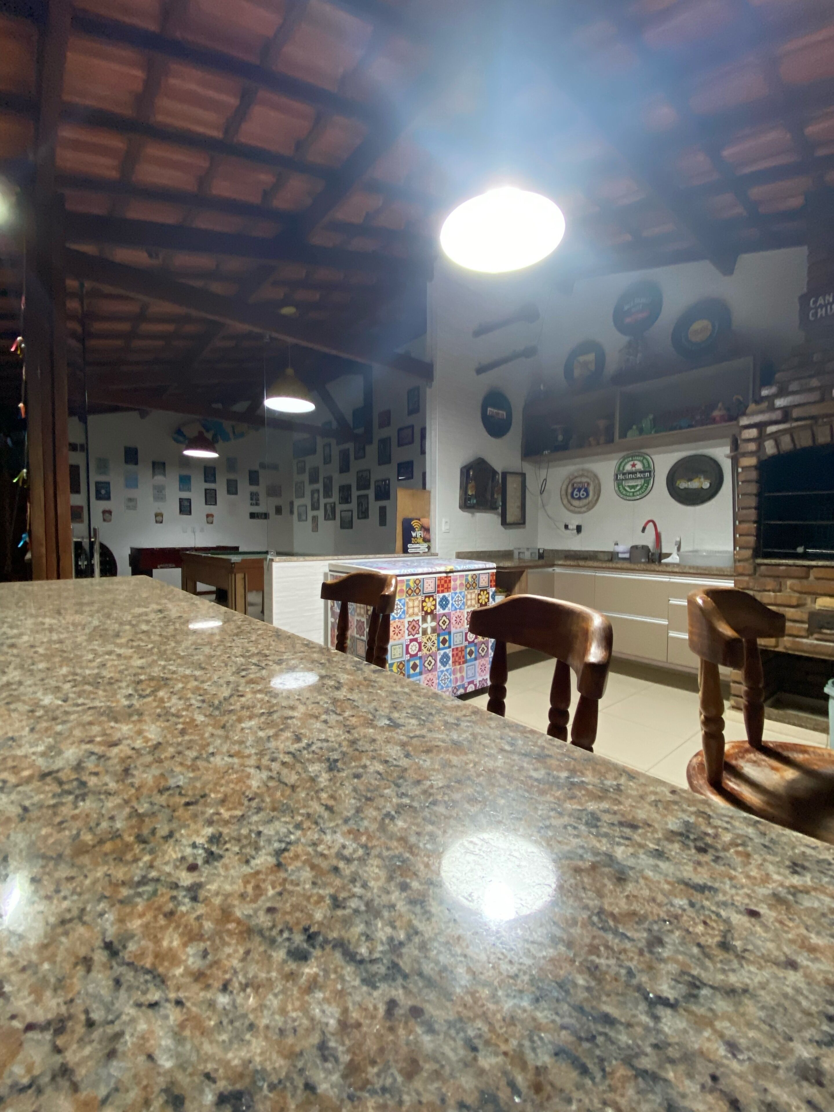 Une cuisine dotée de plans de travail en granit, de chaises en bois et d’une nappe à motifs.