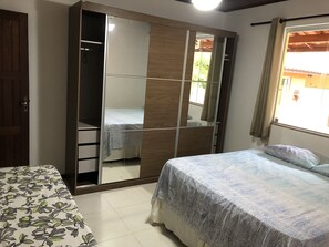 Une chambre à coucher avec un lit, une armoire avec un miroir et une fenêtre avec des rideaux.