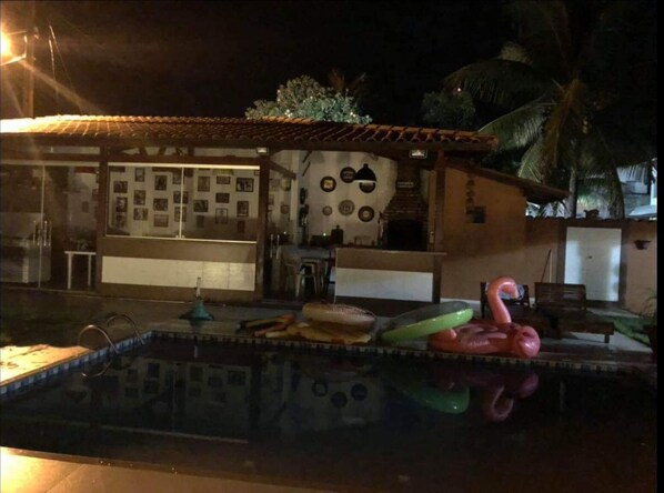 A pool area with a tiled deck, a large inflatable flamingo, and a wall with various decorations. - Best option excellent standard complete, 5 bedrooms practically on the seafront (Ilhéus)
