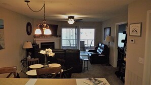 A living room with a fireplace, a dining area with a table and chairs, a sofa, and a ceiling fan. - Fabulous Patio View Overlooking The Main Channel Of Table Rock Lake (Hollister)
