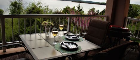A dining table set for two with a view of a lake and hills in the background.