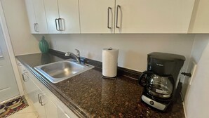 Eine Küche mit Spüle aus Edelstahl, Papierhandtuchspender und einer Kaffeemaschine.