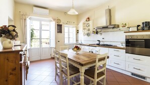A kitchen with white cabinets, a wooden dining table, and a stove. - Historical Center With Large Terrace (Lucca)