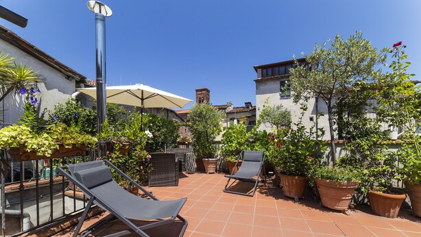 A patio with two lounge chairs, a table, and potted plants. - Historical Center With Large Terrace (Lucca)