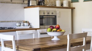 A dining area with a wooden table, white chairs, and a fruit bowl. - Historical Center With Large Terrace (Lucca)