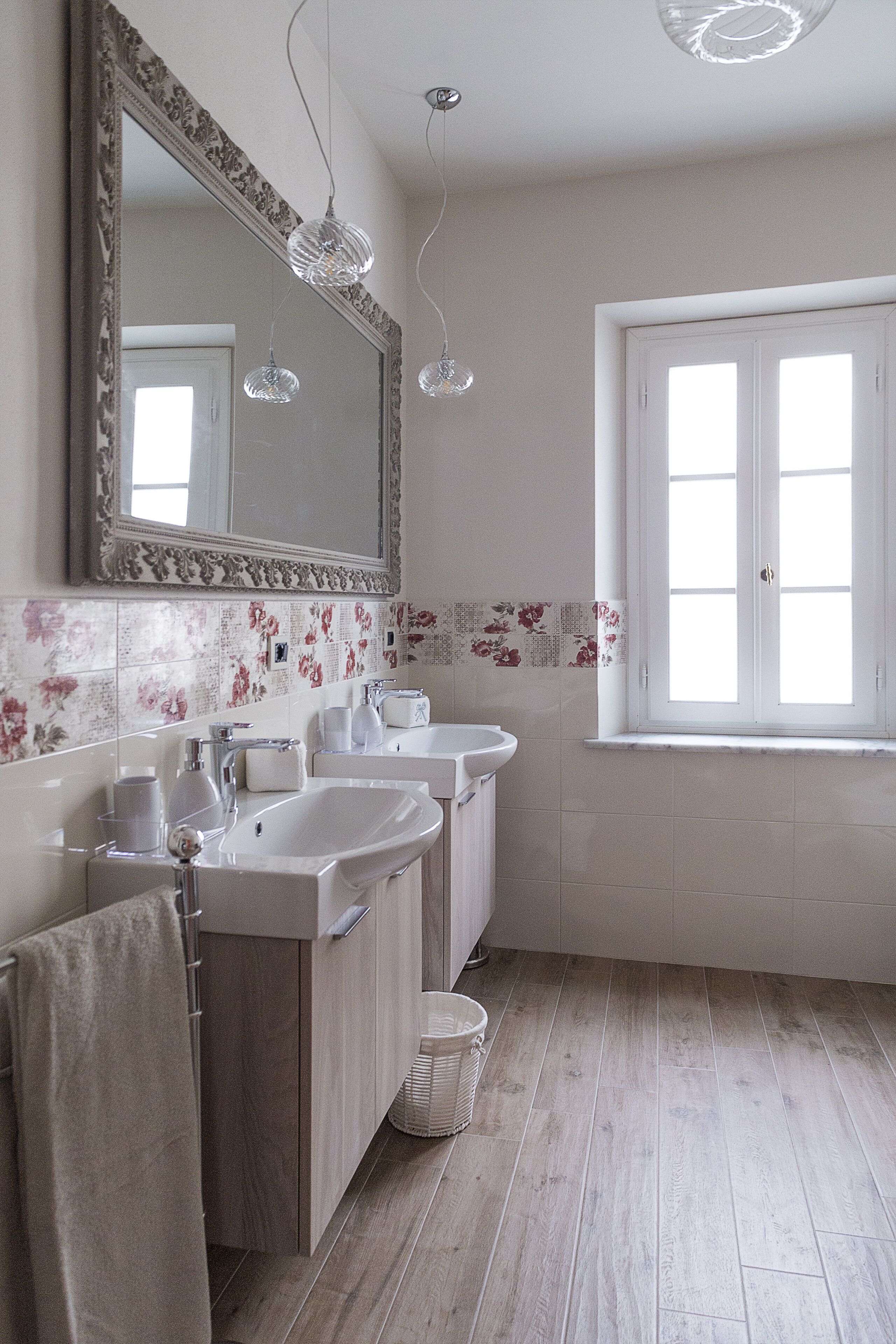 A bathroom with two sinks, a large mirror, and a window.