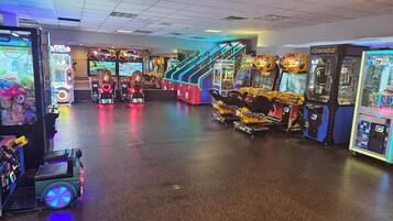An indoor arcade with various gaming machines, including racing and claw-puck games, and a wheelchair-accessible ride.