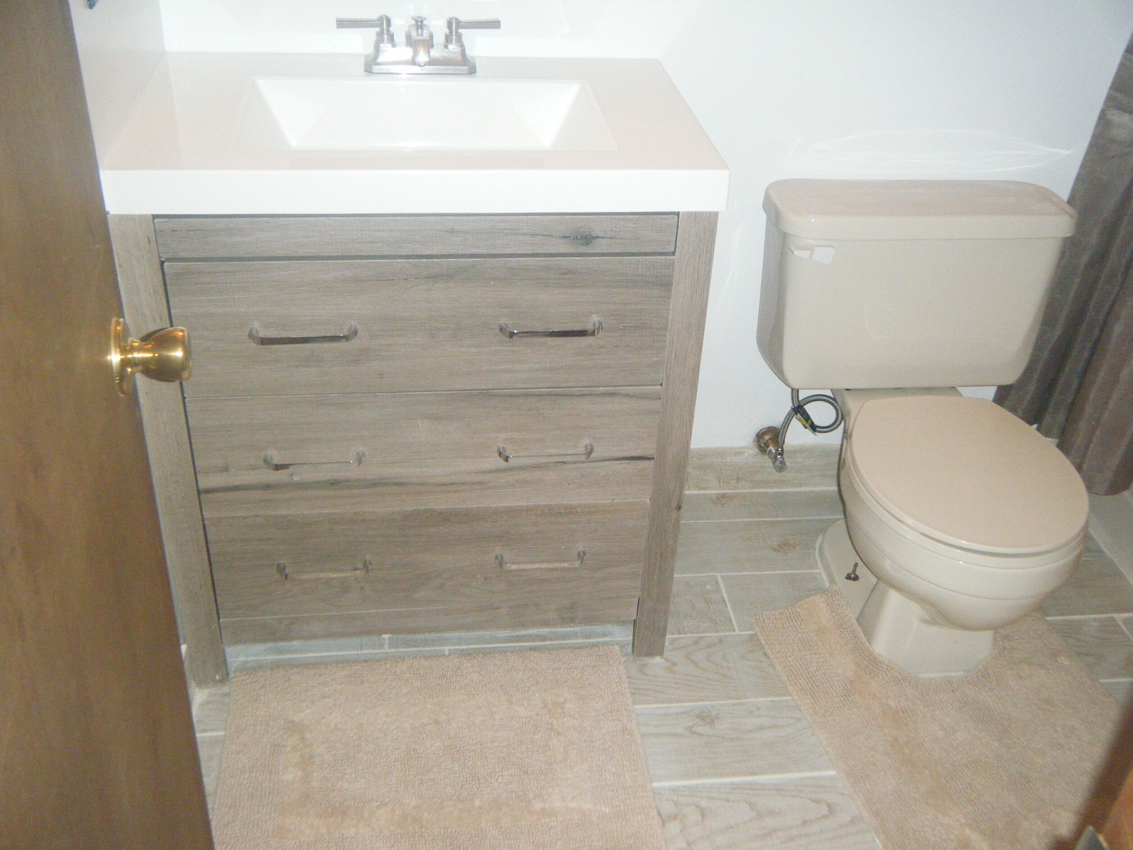 A bathroom with a sink, toilet, and wooden cabinet drawers.