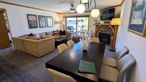 A living room with a sofa, a dining table, and a fireplace. There are framed pictures on the wall and a television above the fireplace. - Luxury Condo w/ FREE WiFi, Parking, Heated Pool, Hot Tubs, Skier Shuttles (Avon)