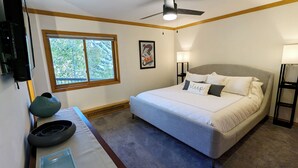 A bedroom with a bed, a window, a ceiling fan, and a nightstand with a lamp. - Luxury Condo w/ FREE WiFi, Parking, Heated Pool, Hot Tubs, Skier Shuttles (Avon)
