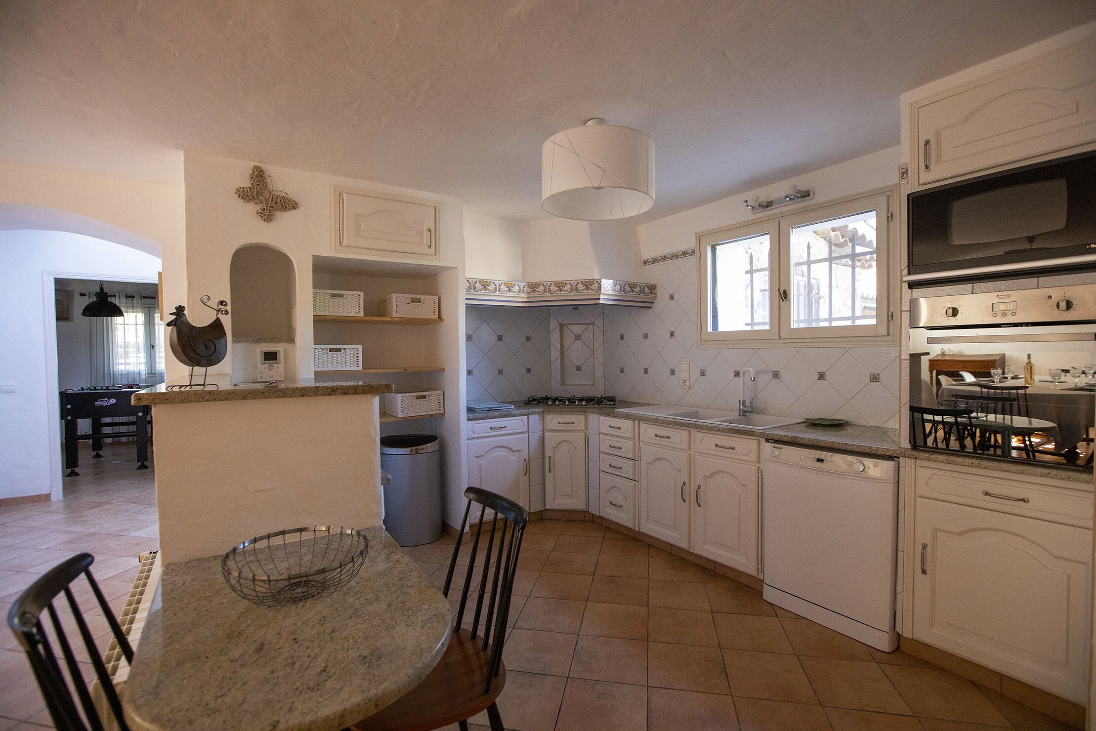 Une cuisine avec des meubles blancs, une cuisinière, un évier et un coin repas comprenant une table et des chaises.