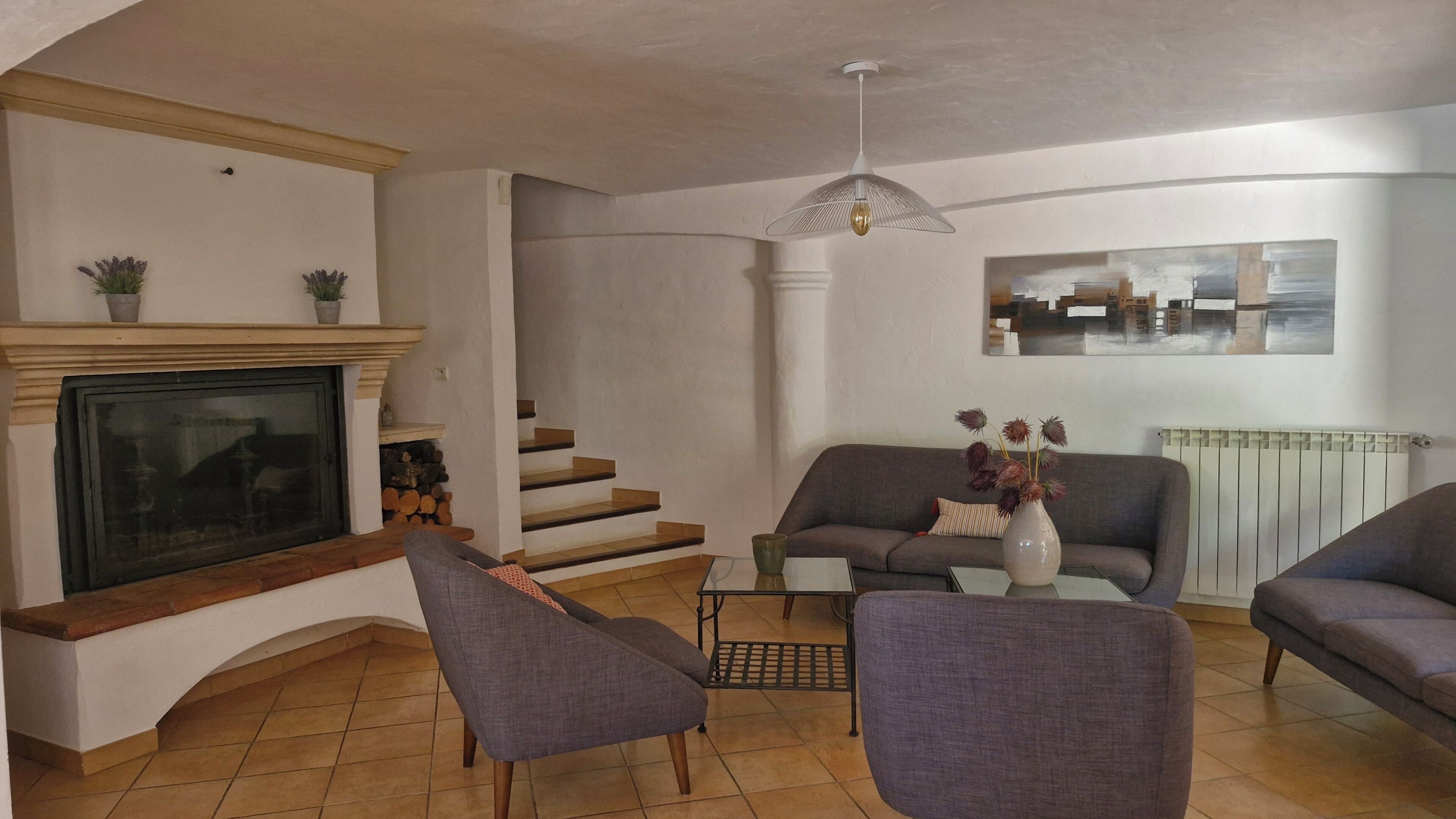 Una sala de estar con chimenea, sofá, sillones, una mesa de centro y una escalera.
