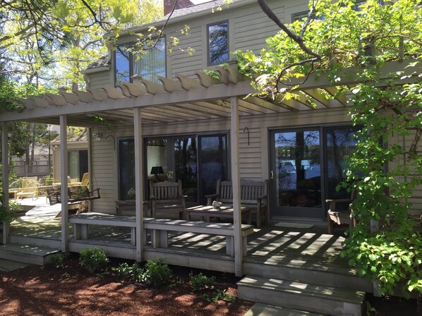 A covered porch with a pergola, outdoor seating, and a view of a lake.