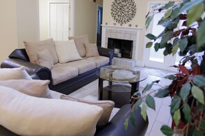 Ein Wohnzimmer mit Sofa, Glastisch und Kamin.