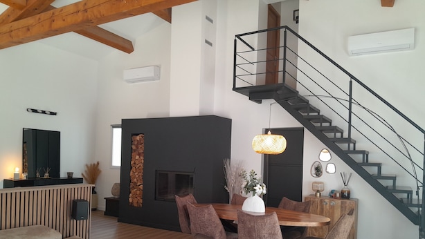 Een moderne woonkamer met een eethoek, een open haard en een wenteltrap.