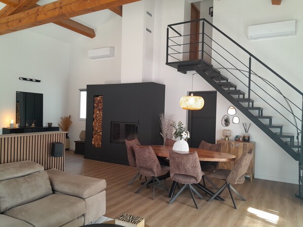 Een moderne woonkamer met een eethoek, een open haard en een wenteltrap.