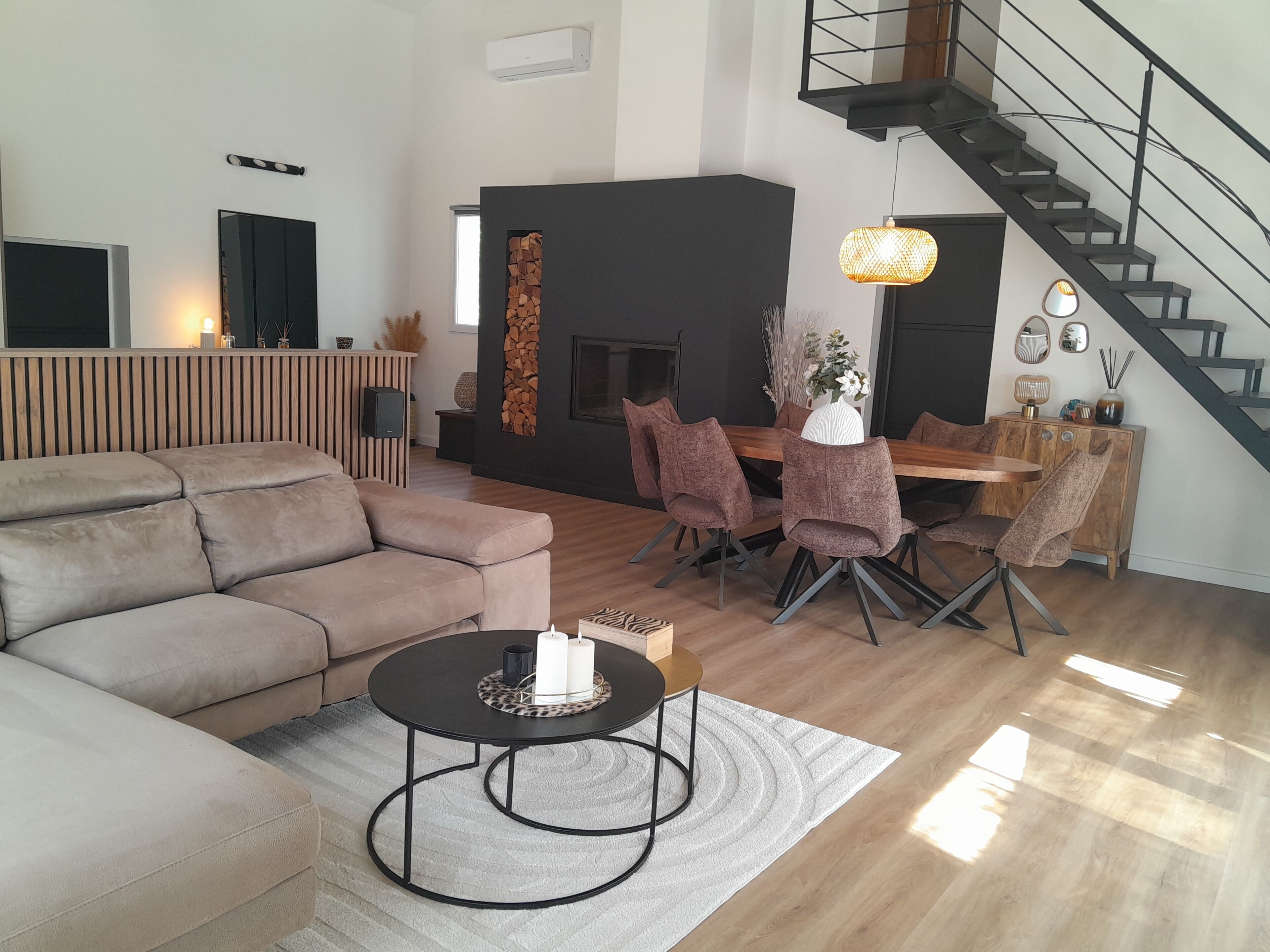 Ein modernes Wohnzimmer mit einer Couch, einem Esstisch, Stühlen, einem Kamin und einer Treppe.