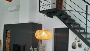 Een modern interieur met een houten eettafel, gestoffeerde stoelen, een open haard, een trap en decoratieve spiegelwanden.