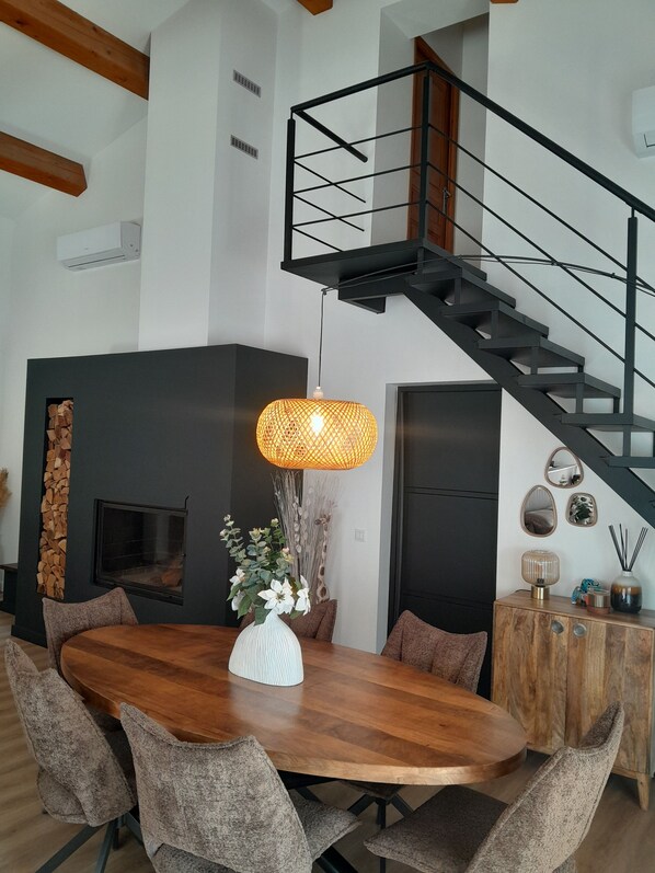 A modern interior with a wooden dining table, upholstered chairs, a fireplace, a staircase, and decorative wall mirrors. - 🌿 contemporary villa between Marseille and Cassis @🌿 🌴⛱️🌴 (Marseille)