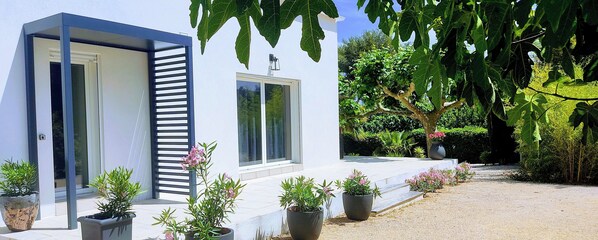 Une maison moderne avec une façade blanche, de grandes fenêtres et une allée gravillonnée.