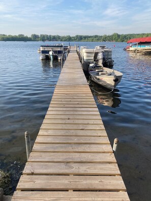 A wooden dock extending into calm water with several boats docked at the end.