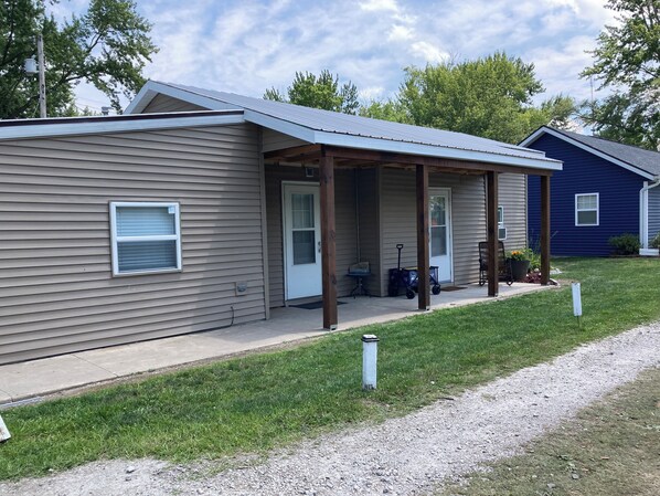 A single-story house with a covered porch, a front door, and a small table with chairs.