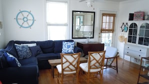 A living room with a dark blue sofa, two wooden chairs, a wooden coffee table, and a white cabinet with glass doors. - 2 Bedroom Lovingly Restored 1925  Cottage 1 1/2 Blocks From Beach (Tybee Island)