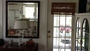 A room with a large mirror, a lamp, a dresser, and a door leading outside. - 2 Bedroom Lovingly Restored 1925  Cottage 1 1/2 Blocks From Beach (Tybee Island)
