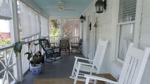 A covered porch with white wooden chairs, a table, and a potted plant. - 2 Bedroom Lovingly Restored 1925  Cottage 1 1/2 Blocks From Beach (Tybee Island)