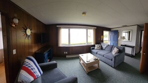 A living room with a sofa, a coffee table, a TV, and a fireplace. - Located In The Heart Of Meredith Bay (Meredith)