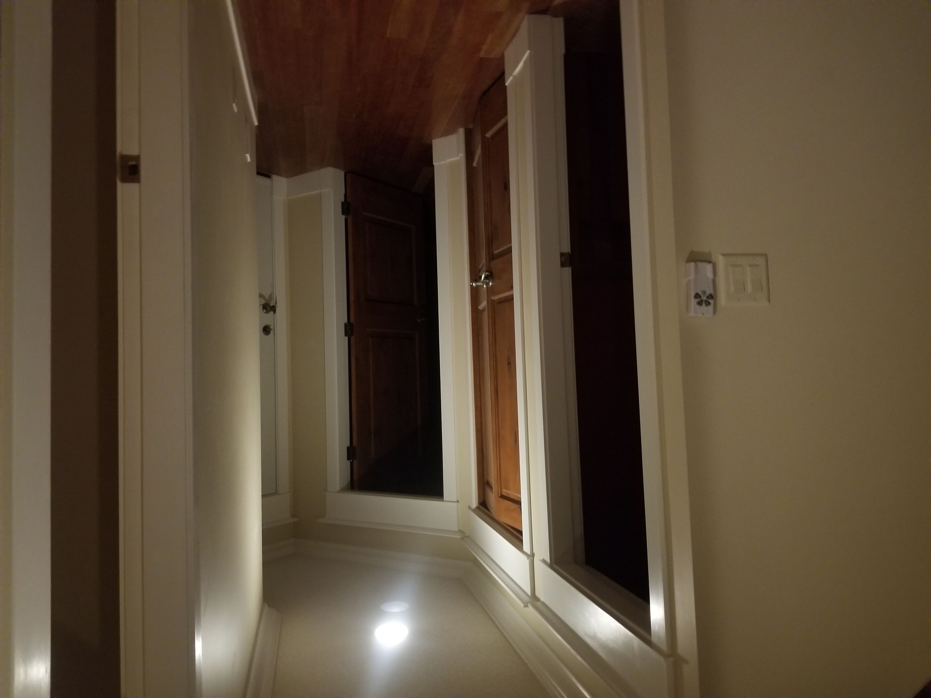 A narrow hallway with wooden ceiling and white walls.