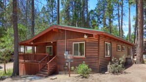A rustic cabin with a wooden exterior, a front porch, and a staircase leading to a deck.