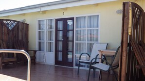 A patio with a wooden fence, a door, and a table with chairs.