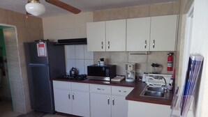 A compact kitchen with white cabinets, a black refrigerator, a microwave, a coffee maker, and a sink.