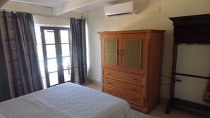 A bedroom with a bed, a wooden wardrobe, and a window with curtains.
