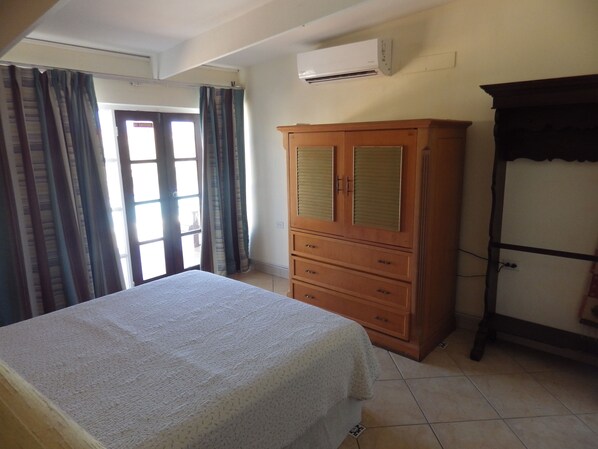 A bedroom with a bed, a wooden wardrobe, and a window with curtains.