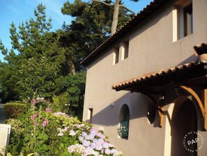 Un bâtiment à la façade beige, doté d’un toit en tuiles et d’une petite fenêtre en arc de cercle.