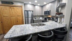 Una cocina moderna con encimeras de granito, electrodomésticos de acero inoxidable y armarios de madera.