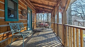 A wooden porch with a bench, a table with chairs, and a view of trees. - Cabin on the Hill family friendly (Russell Springs)