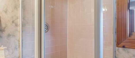 Un cerramiento de ducha con puerta de cristal, vigas de madera en el techo y suelo de baldosas.