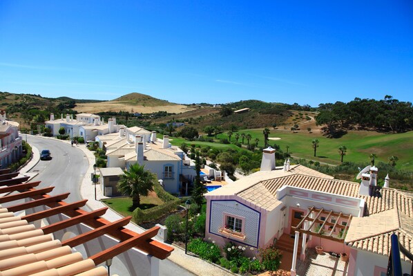 A coastal town with white buildings, a curved road, and a golf course in the background. - Luxury Linked Villa, Superb Views of Golf Course, Best Pool, Fabulous Beaches (Budens)