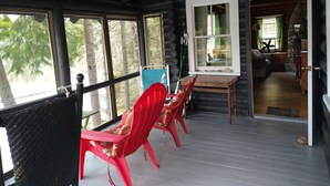 Una baita di legno con veranda, un tavolo e sedie rosse.
