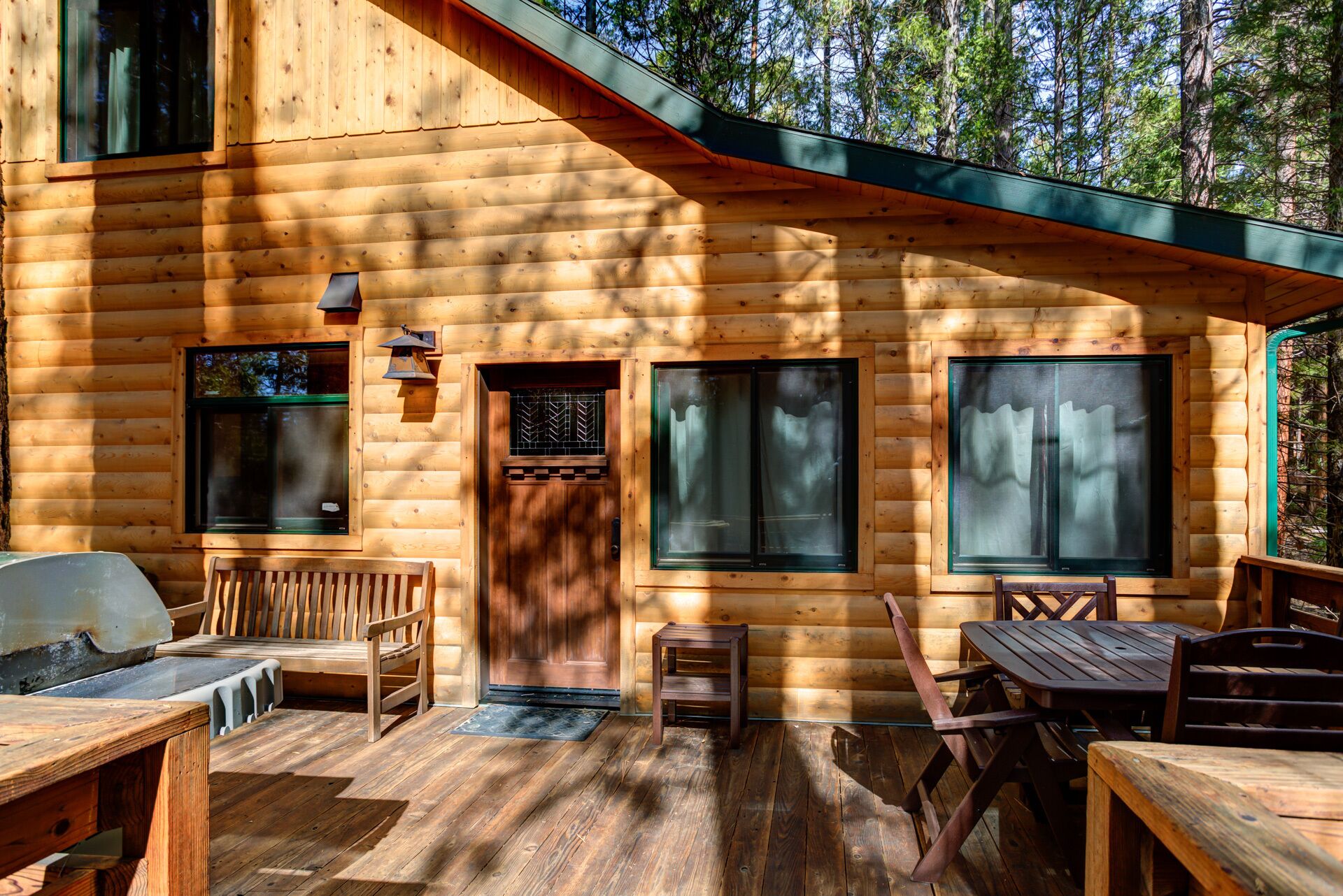 Une cabane en bois avec une véranda, un banc et une table.