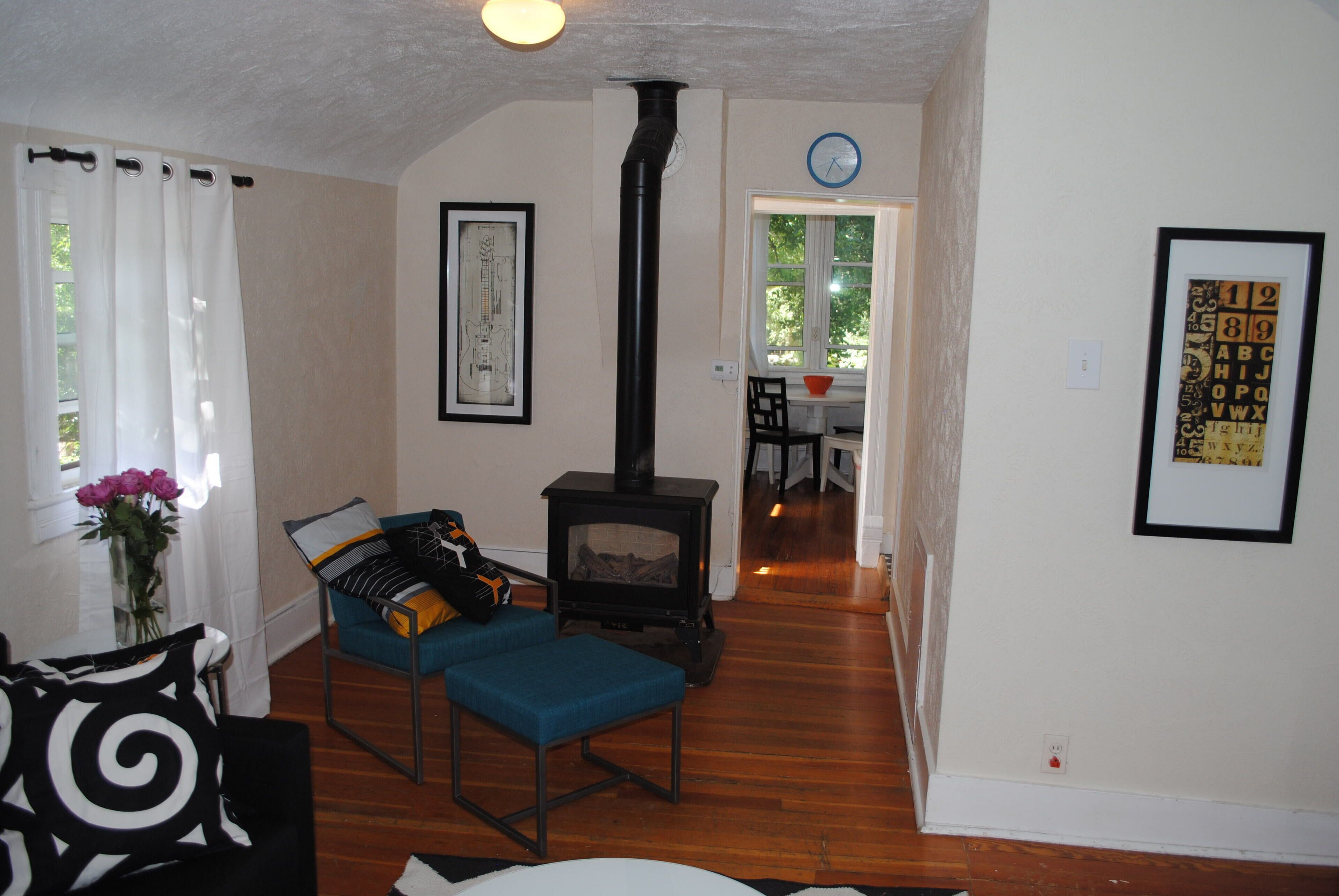 A living room with a fireplace, a dining area, and a kitchen visible in the background.