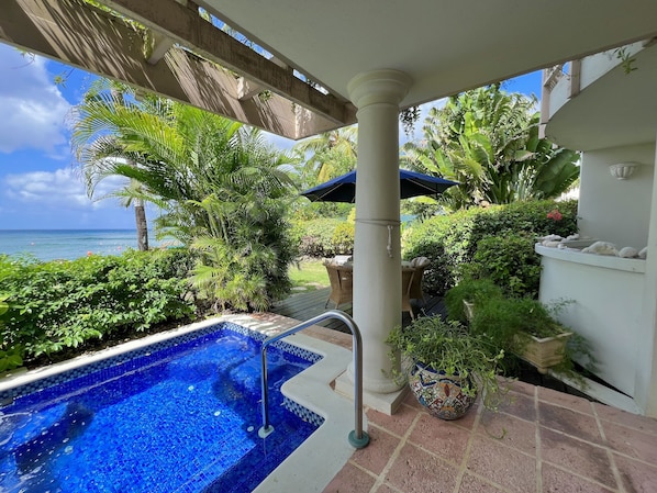 A pool area with a view of the ocean, surrounded by lush greenery and a pergola. - Reeds House on Reeds Bay. On the sea with Wonderful Sea Views From Every Room. (Carlton)